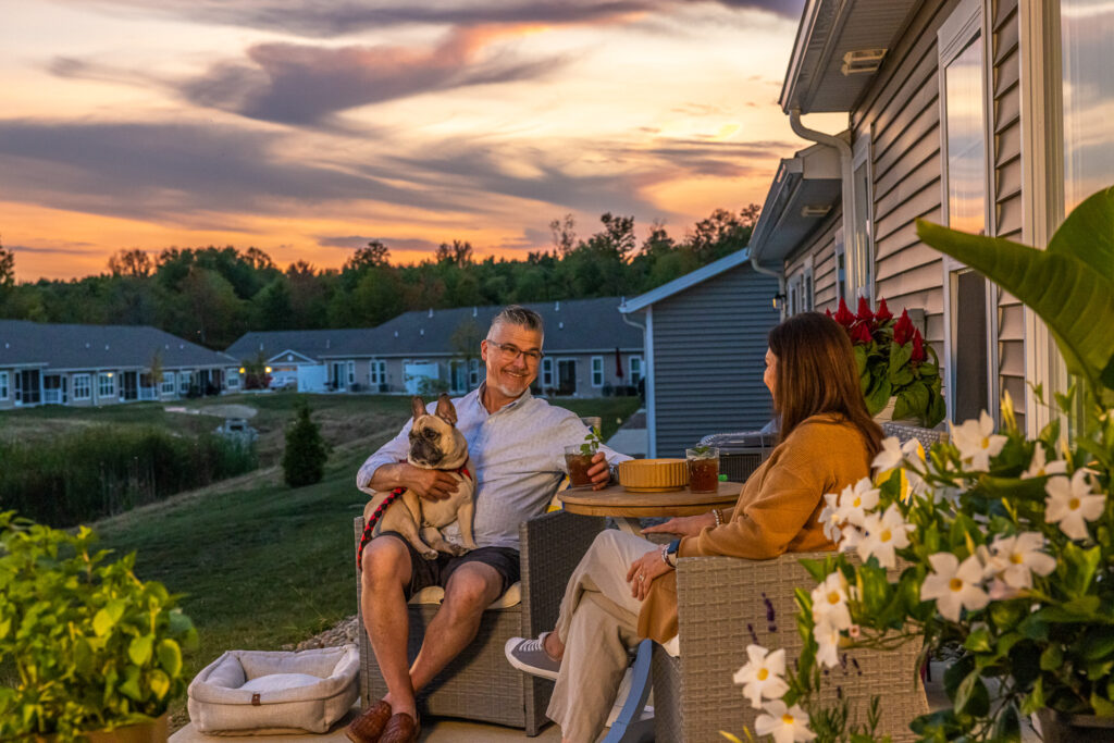two people sitting on a patio with their dog